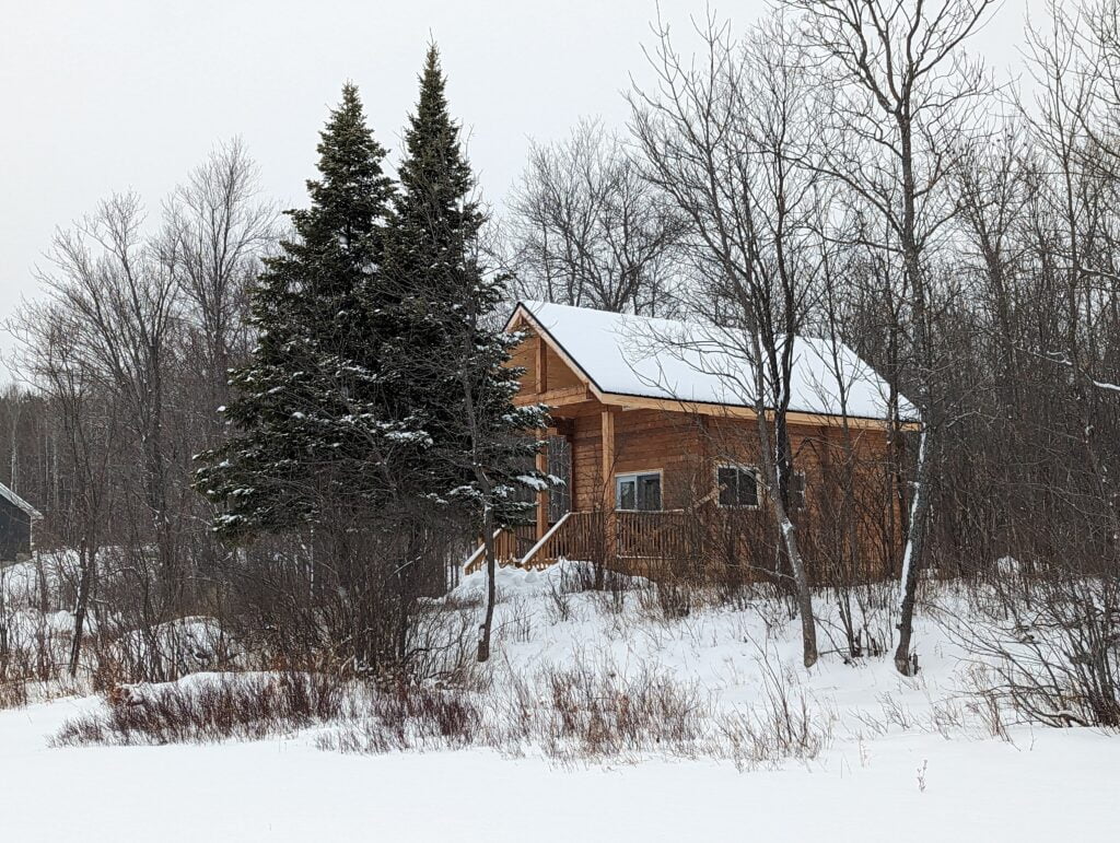 A cozy cabin surrounded by snow-covered trees, offering a serene winter retreat.